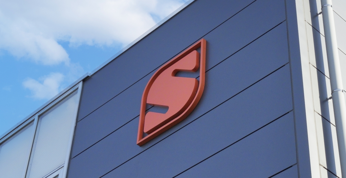 青空を背景にした企業ビル外壁に掲げられた新日本電子株式会社のロゴ